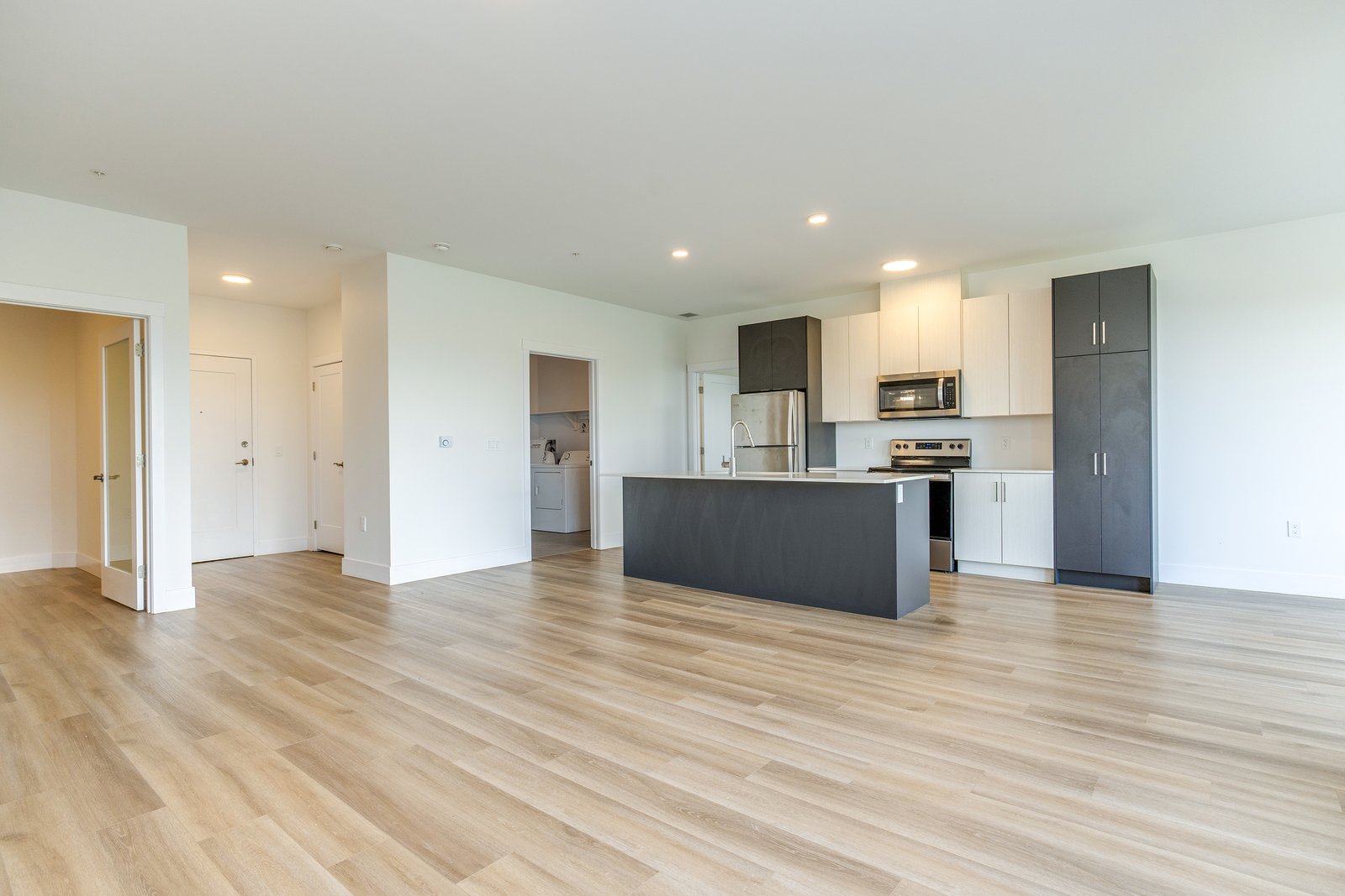 Open-concept kitchen with dark cabinetry, unfurnished