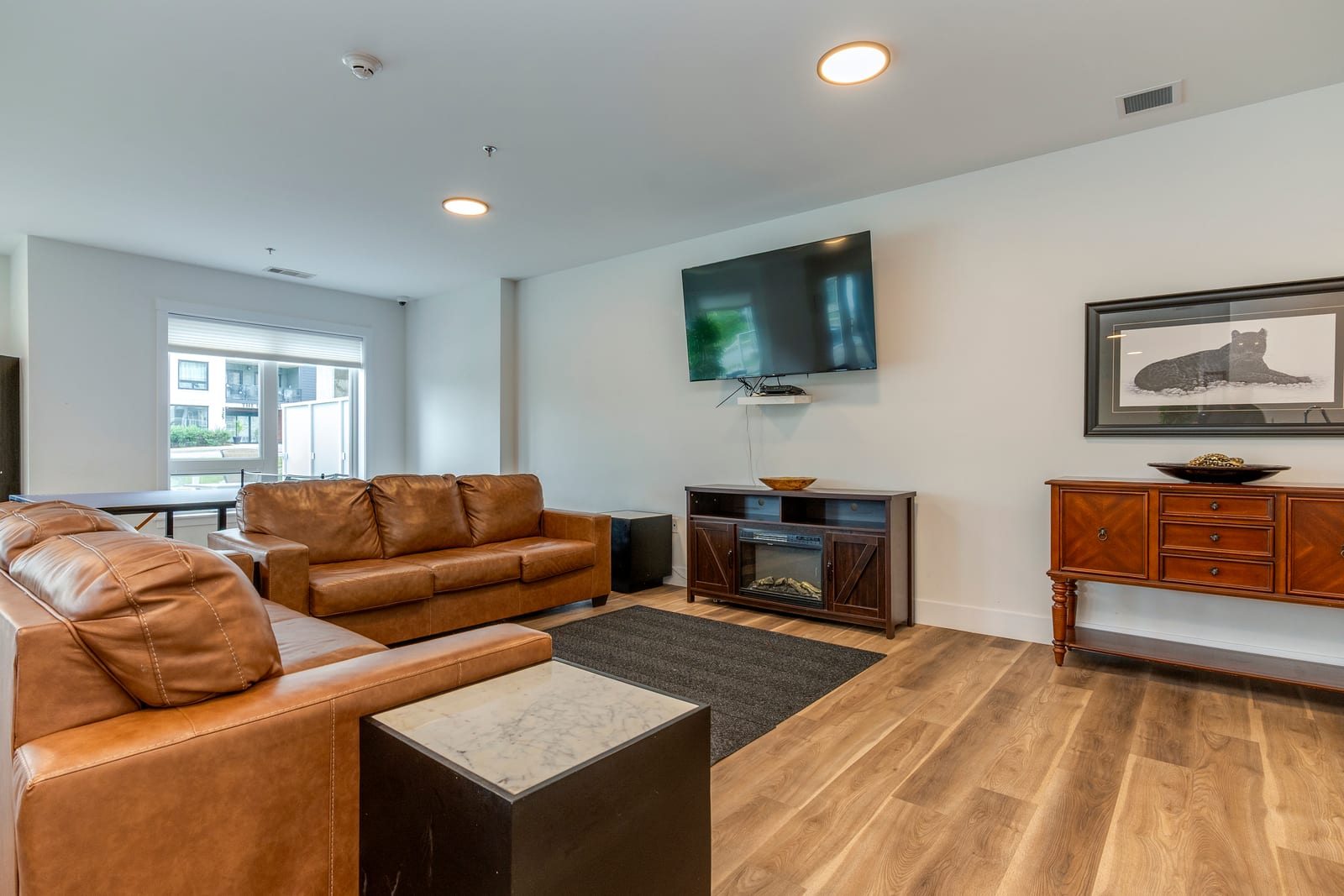 Tenants' lounge with leather seating, a wall-mounted TV, and a fireplace console